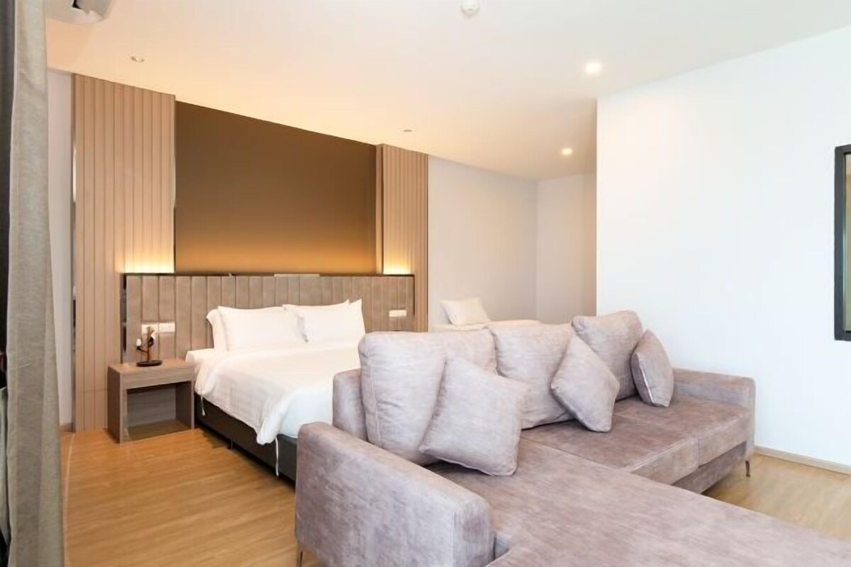 Un dormitorio moderno con una cama, un sofá y una mesita de noche.