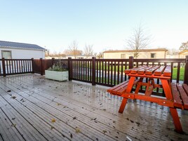 A wooden deck with a picnic table, a wooden fence, and a planter box.