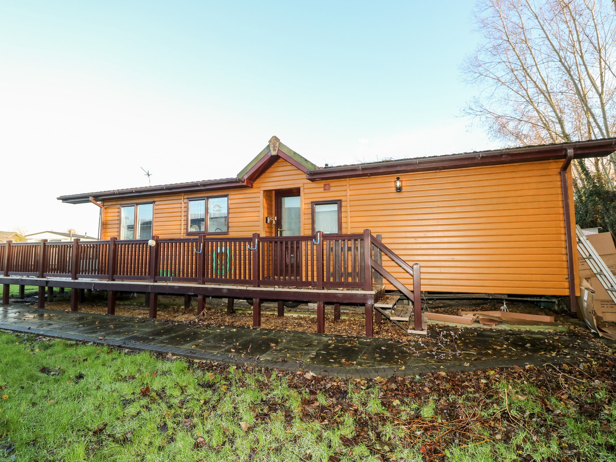 A wooden cabin with a deck, a front door, and windows.
