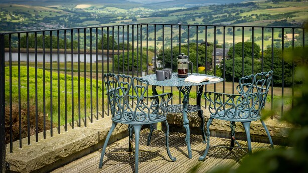 Un balcón con mesa y sillas con vistas a un paisaje pintoresco.