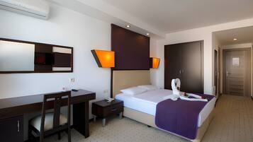 A hotel room with a bed, desk, chair, and a mirror.