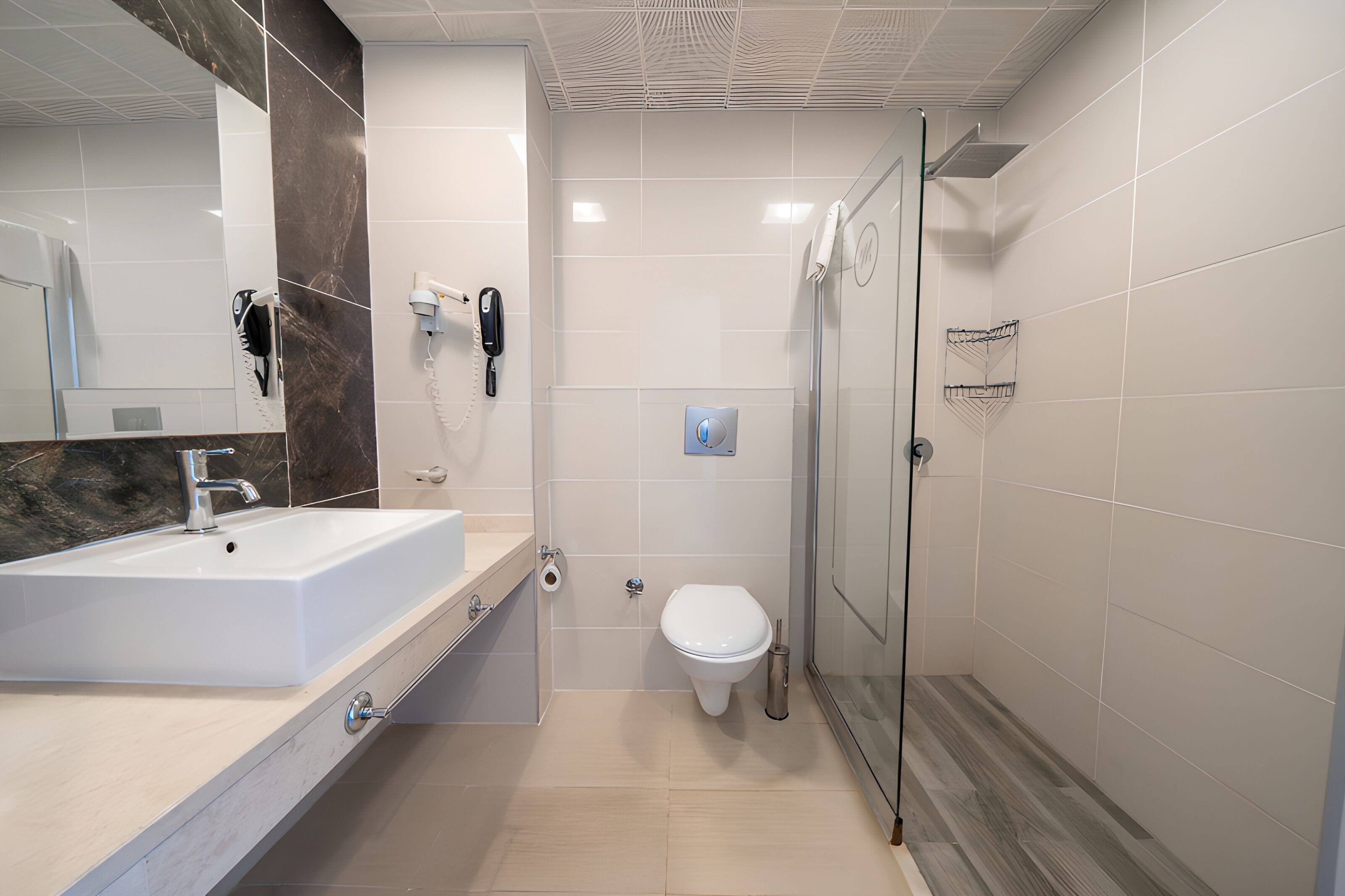 A modern bathroom with a large sink, a toilet, and a glass-enclosed shower.