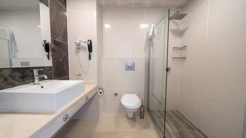 A modern bathroom with a large sink, a toilet, and a glass-enclosed shower.