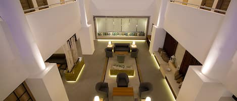 A spacious lobby with a central seating area, a reception desk, and a high ceiling with natural light.