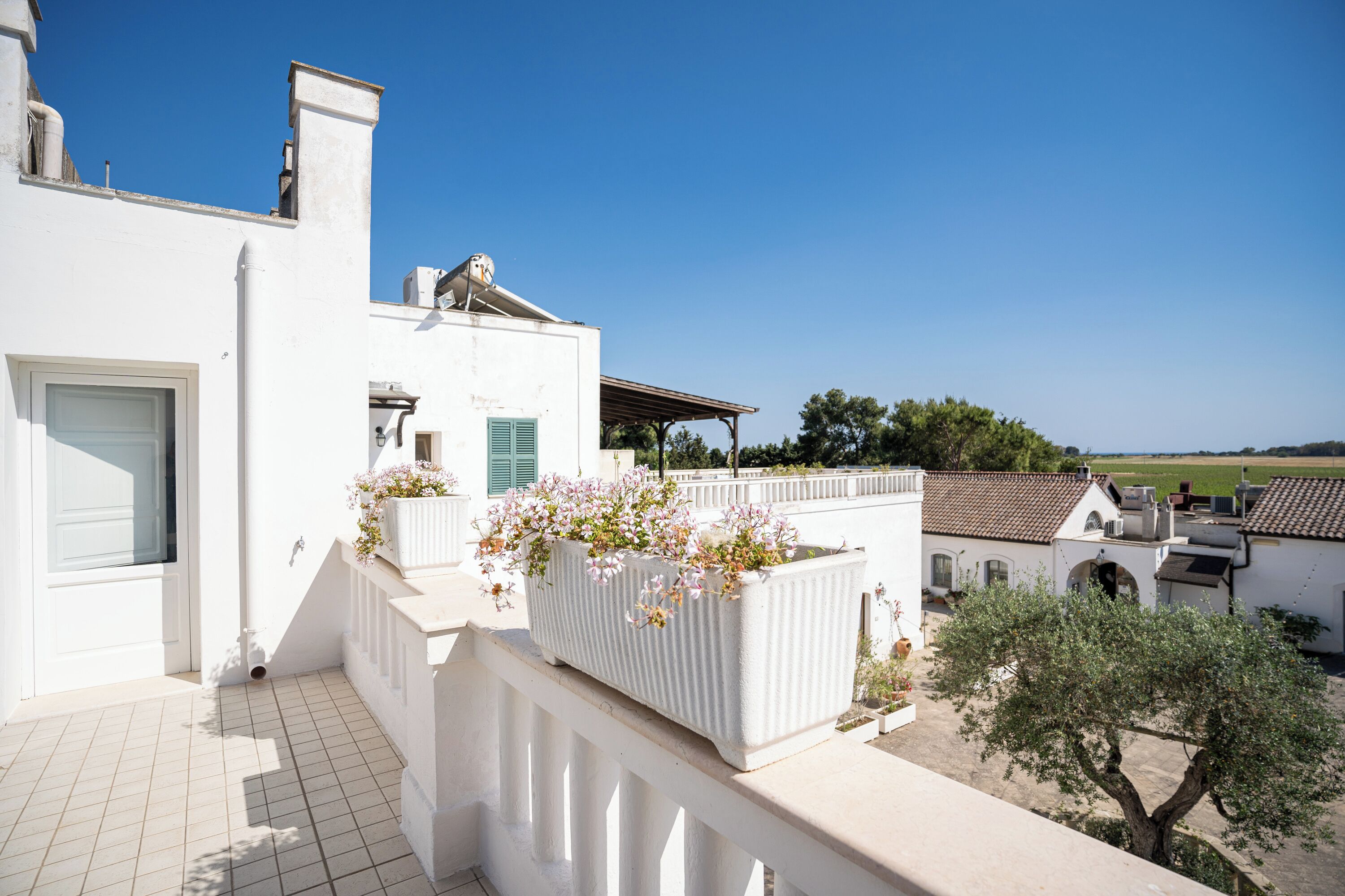 A white building with a tiled balcony and a flower planter.