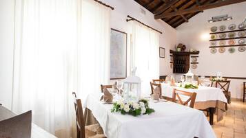 A dining area with white tablecloths, wooden chairs, and a white lantern centerpiece.