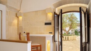 A kitchen with a bar area, a chair, and a view of the outside. - Tenuta del Barco (Taranto)