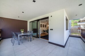 A modern interior with a dining area, sliding glass doors leading to a balcony, and a view of the outside.