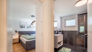 A modern bedroom with a bed, bedside table, and artwork on the wall. - Apartment 'Sankt Martin' with Mountain View, Private Terrace and Wi-Fi (Sankt Martin)