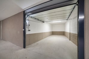 A clean, empty parking garage with concrete floors and walls, a metal door frame, and a ceiling with fluorescent lighting.