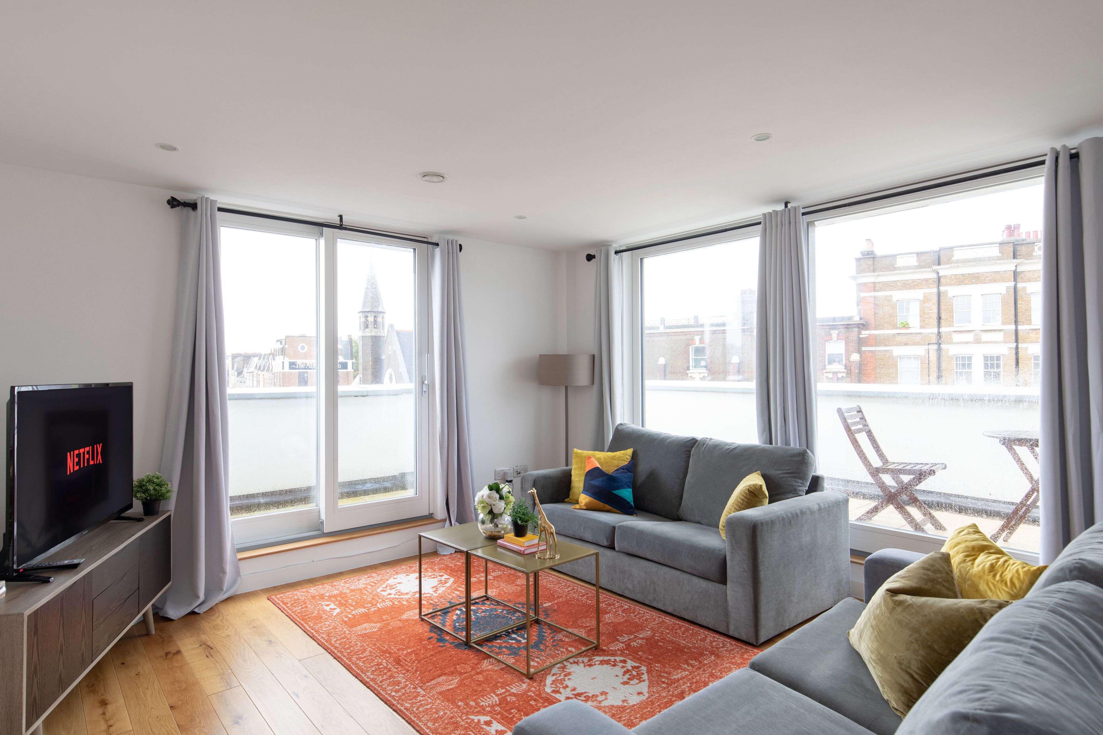 Una sala de estar moderna con un sofá gris, una mesa de centro y un televisor que muestra Netflix.