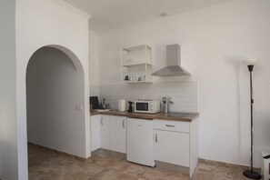 A modern kitchen with white cabinetry, a microwave, a coffee maker, and a built-in oven. - Apartment Siempreviva on Finca Falcon Cresta (Agüimes)
