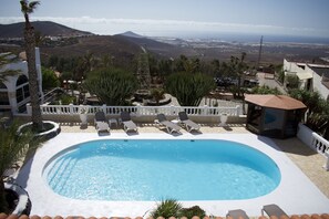 A swimming pool with lounge chairs, surrounded by cacti and a mountainous landscape. - Apartment Siempreviva on Finca Falcon Cresta (Agüimes)