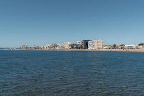 Et kysthotel med flere etager, en strand i baggrunden og klare himmel.