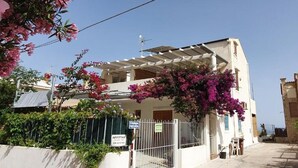 Edifici de dues plantes amb un porxo cobert, un senyal de carrer privat i una entrada tancada per una reixa.