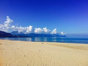 A beach with a clear sky and mountains in the background.