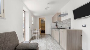 Une cuisine moderne dotée d’une cuisinière intégrée, de meubles en bois et d’un téléviseur à écran plat fixé au mur.