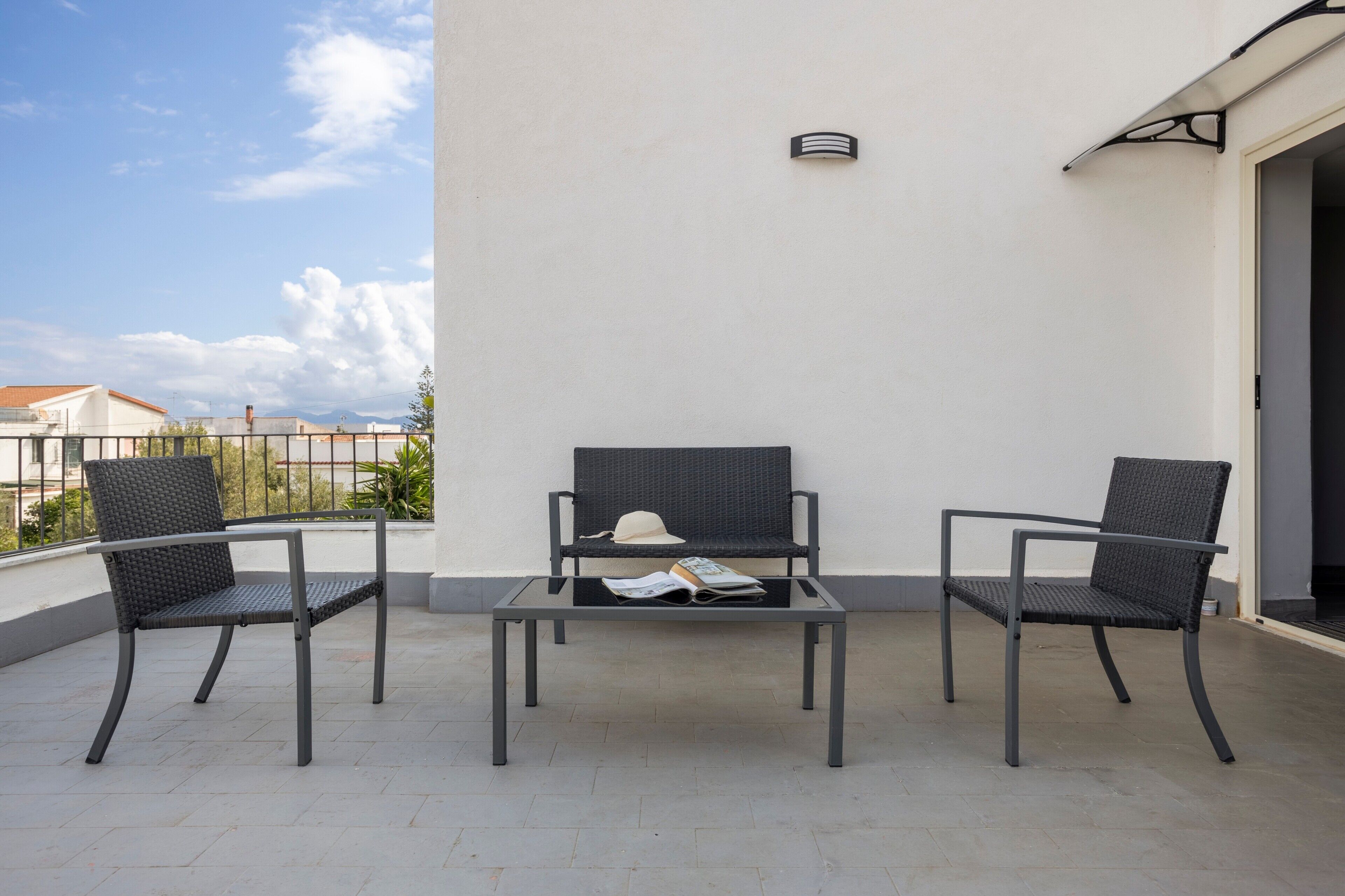 A balcony with two chairs and a table, a hat, and a book on the table.