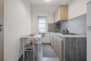 A compact kitchen with a dining table, chairs, and a window.