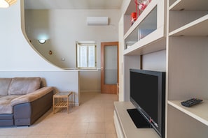 A living room with a sofa, TV, and shelves.