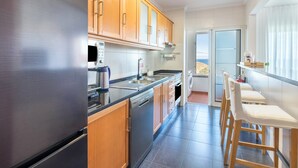 Una cocina moderna con electrodomésticos de acero inoxidable, armarios de madera y un comedor con sillas.