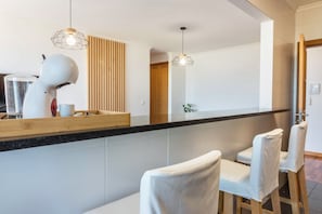 Une cuisine moderne équipée d’un plan de travail, d’un sèche-cheveux et de deux chaises.