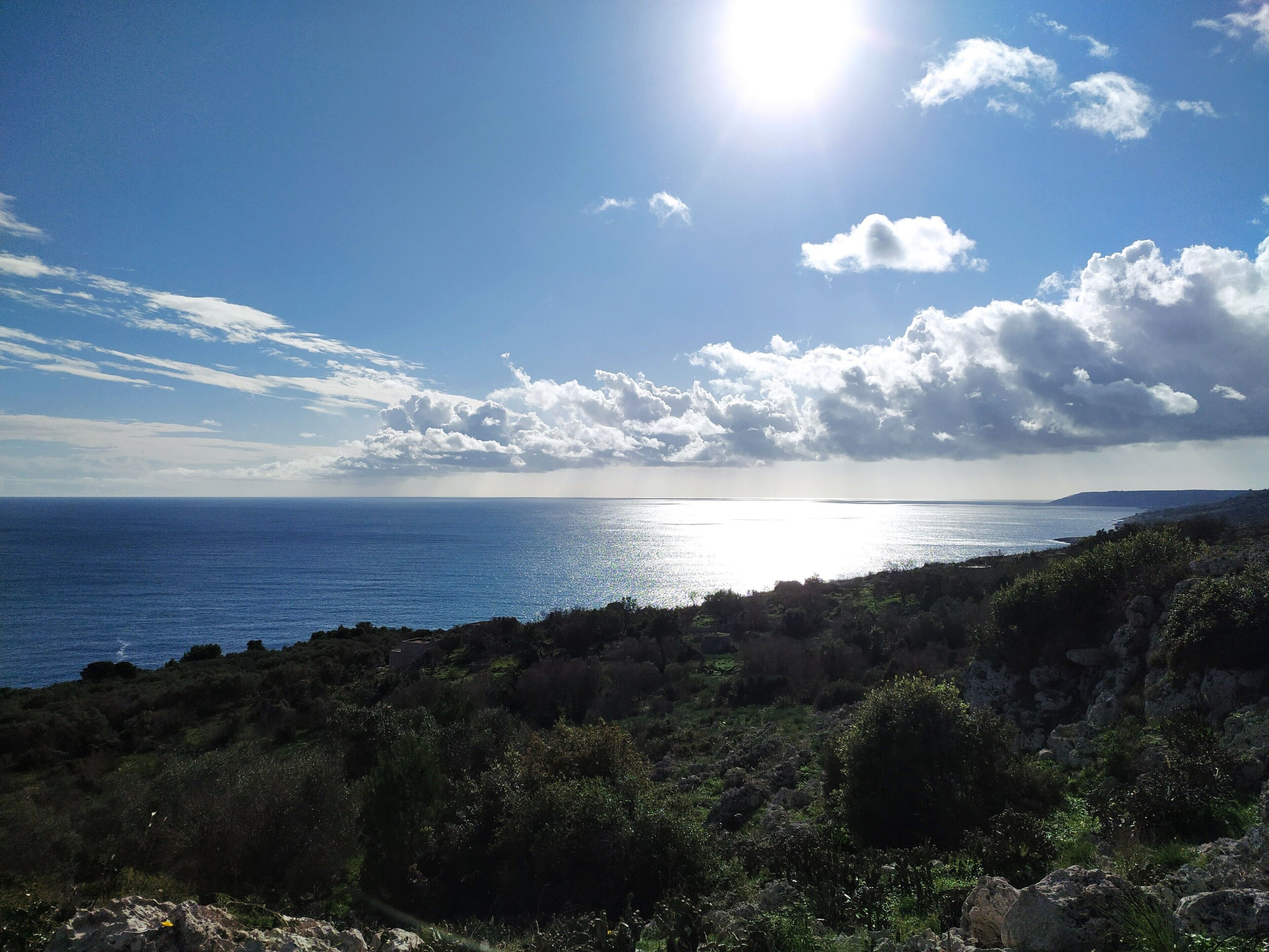 Eine Küstenlandschaft mit blauem Himmel, Blick auf das Meer und felsigem Gelände.