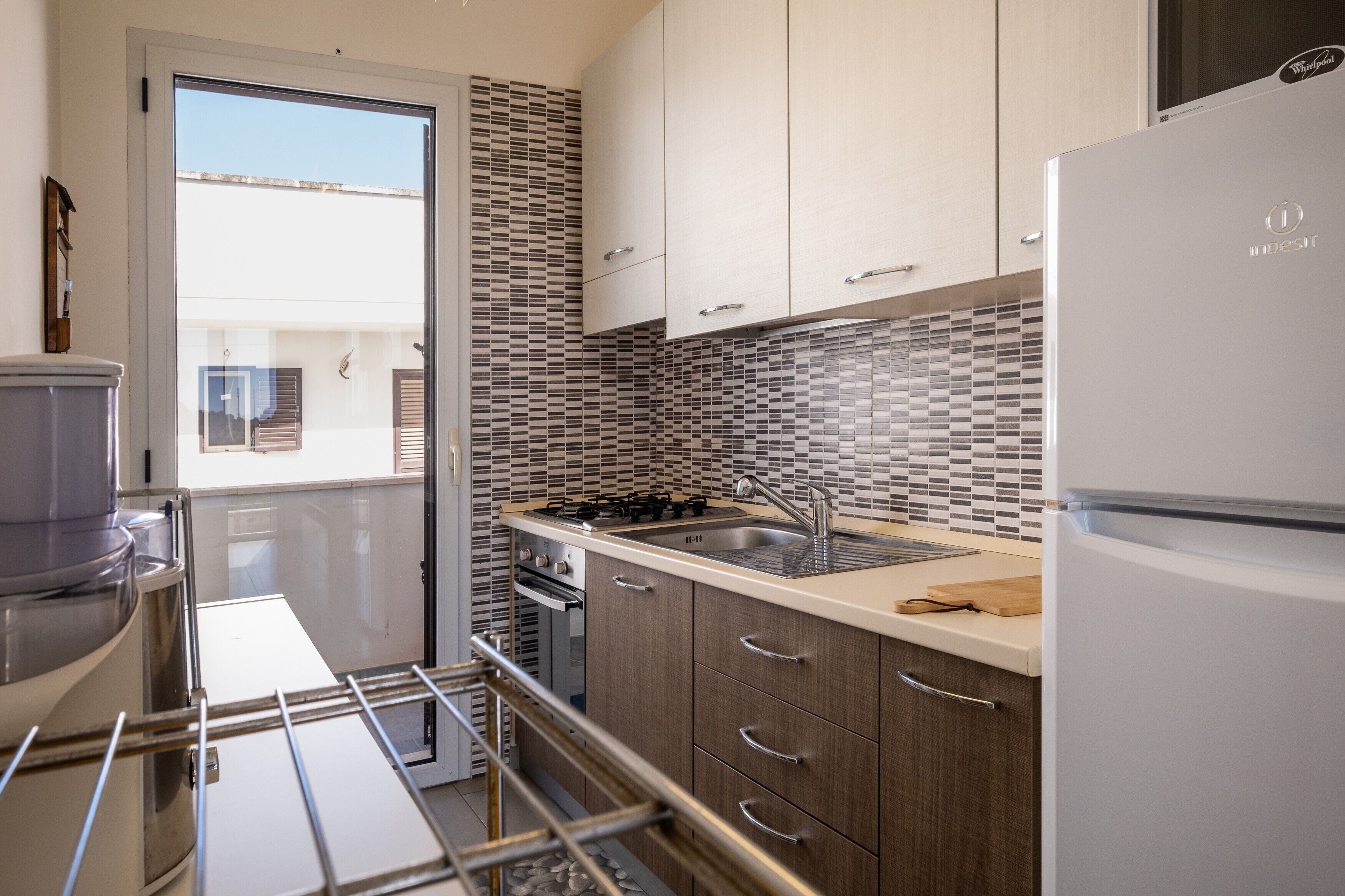 A modern kitchen with a built-in oven, a sink, and a refrigerator.