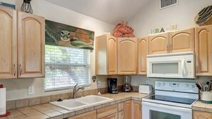 A kitchen with wooden cabinets, a microwave, a stove, a sink, and a window with blinds.