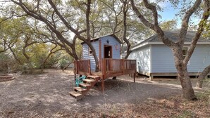 A small wooden structure with a star and American flag, surrounded by trees and a house.