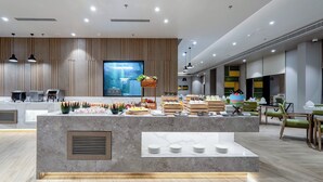 A modern reception area with a marble counter, a large screen, and a buffet setup. - Holiday Inn Katra Vaishno Devi by IHG (Reasi)