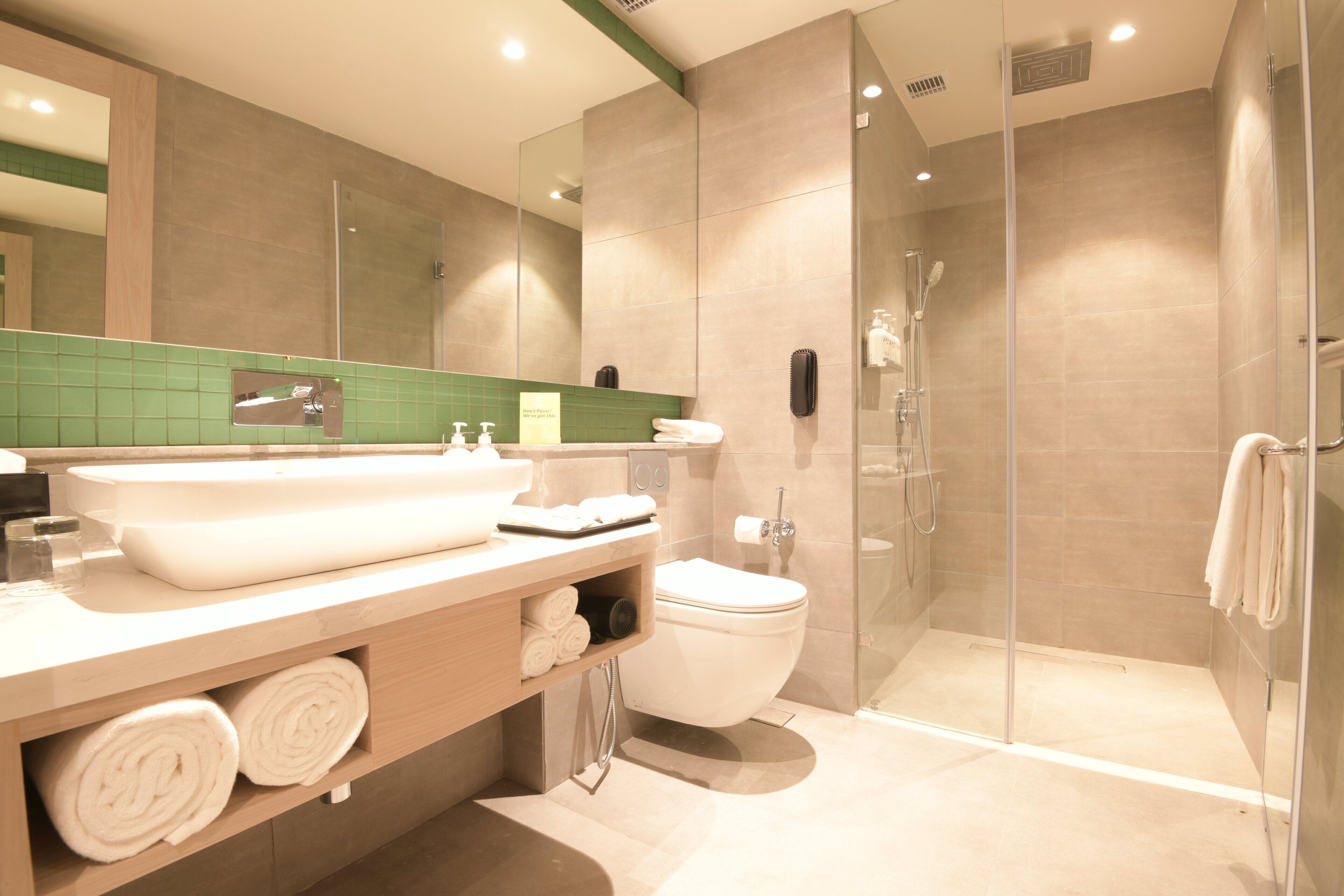 Un baño moderno con un lavabo grande, inodoro y cabina de ducha con paredes de vidrio.
