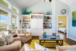 A living room with a sofa, coffee table, and a bookshelf filled with decorative items.