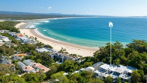 Un quartier résidentiel en bord de mer, avec des propriétés donnant sur la plage, une vue dégagée sur l’océan et une maison blanche emblématique qui se distingue.