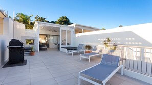 Enjoy al fresco dining and relaxation in this beautifully designed patio area with a barbecue grill, lounge chairs, and a table.