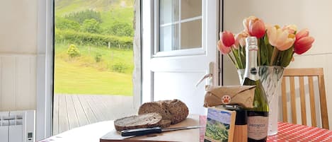 Una mesa con mantel de lunares, una botella de Prosecco, una hogaza de pan y un ramo de tulipanes.