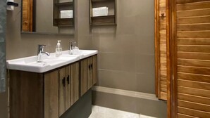 A modern bathroom with a large mirror, two sinks, wooden cabinets, and a towel rack. - Casa Marina Huérfanos (Santiago)