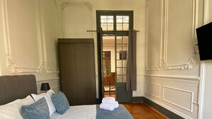 A hotel room with a large bed, a wardrobe, a television, and a door leading to another room. - Casa Marina Huérfanos (Santiago)