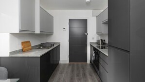 A modern kitchen with dark cabinetry, a central island, and a built-in oven.