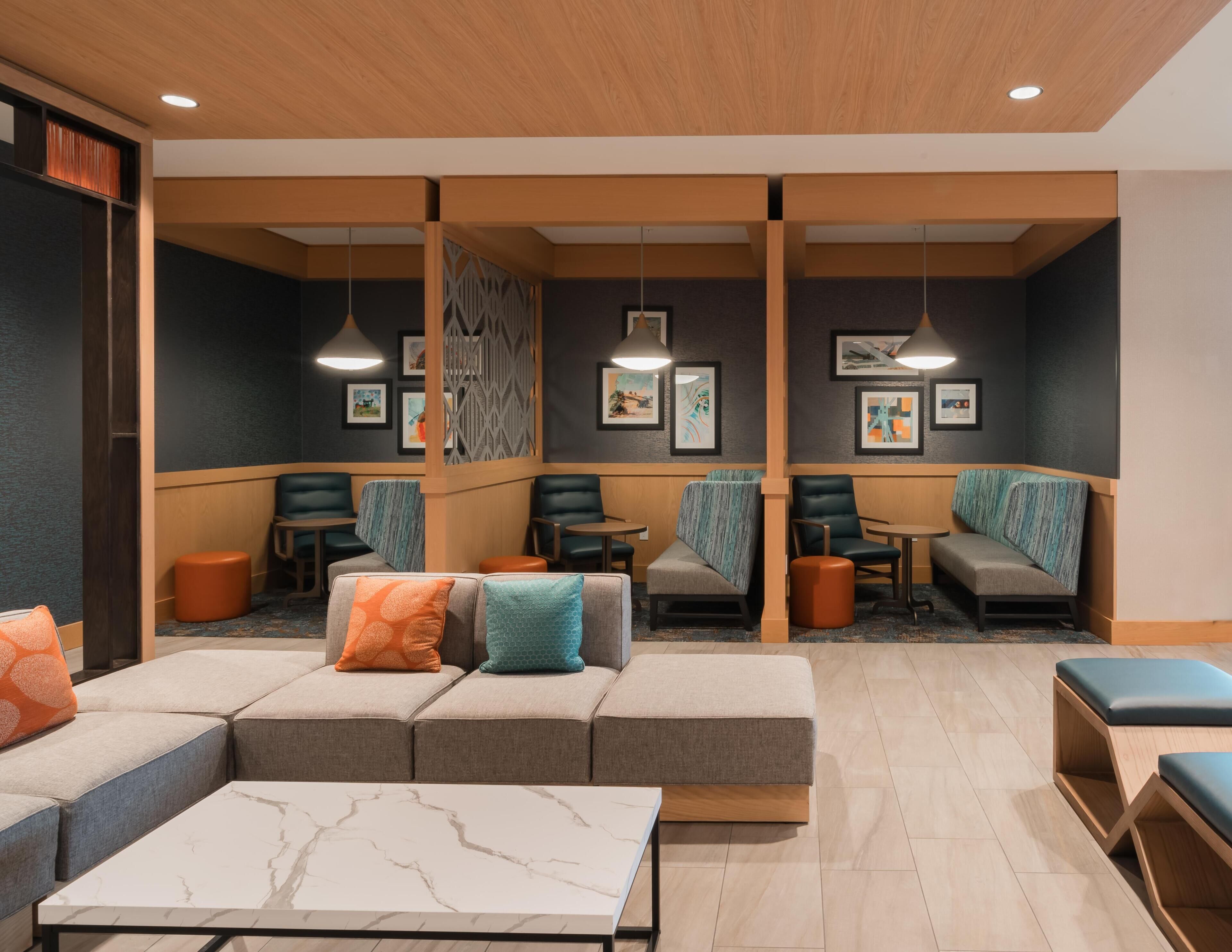 A modern lounge area with seating arrangements, including sofas and chairs, and a marble-tiled coffee table.