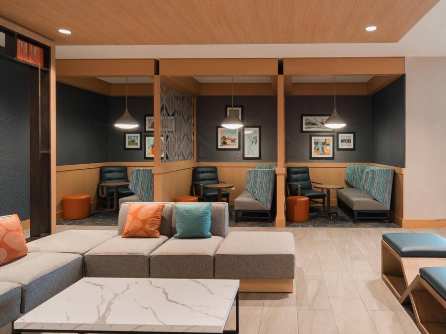 Un'elegante area lounge con posti a sedere, tra cui divani e poltrone, e un tavolino da caffè in marmo.