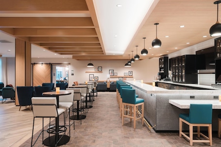A modern restaurant with a bar area, multiple seating options, and a kitchen in the background.