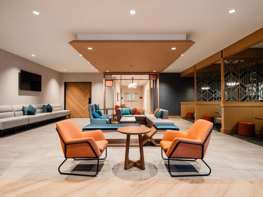 A modern lobby with a seating area, a wooden ceiling, and a patterned wall.