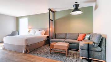 Un dormitorio moderno con cama, sofá, una mesita y una lámpara colgante.