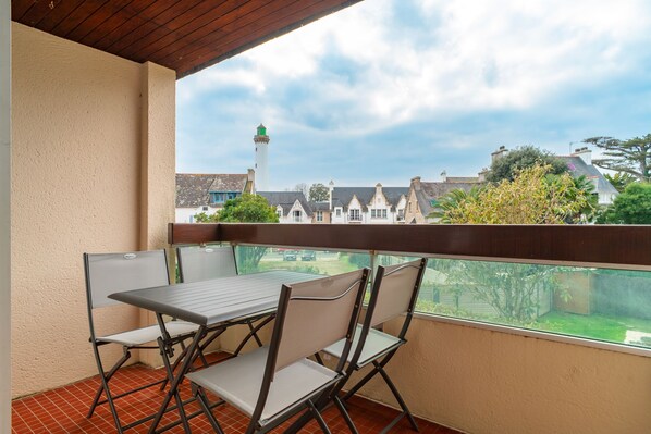 A balcony with a table and chairs, overlooking a village with traditional houses and a lighthouse. - Ty Menez - Proche plage pour 4 (Benodet)