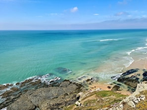 Un paysage côtier caractérisé par une eau turquoise et limpide, des falaises rocheuses et une plage de sable.