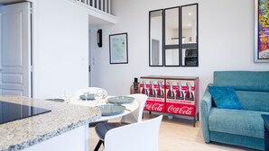 Une cuisine moderne avec un coin repas, un canapé et un réfrigérateur Coca-Cola.