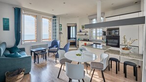 Un salon moderne comprenant un canapé, une table à manger et des chaises. Il y a également un coin cuisine avec une cuisinière et un évier.
