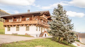A wooden chalet with a balcony, a staircase, and a large evergreen tree in front. - Apartment in Mittersill near KitzSki Lift (Mittersill)
