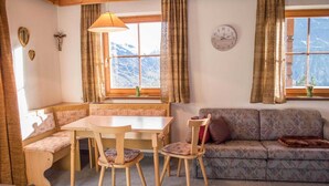 A cozy room with a wooden table and chairs, a sofa, and a bench. There are curtains on the windows, and a clock on the wall. - Apartment in Mittersill near KitzSki Lift (Mittersill)